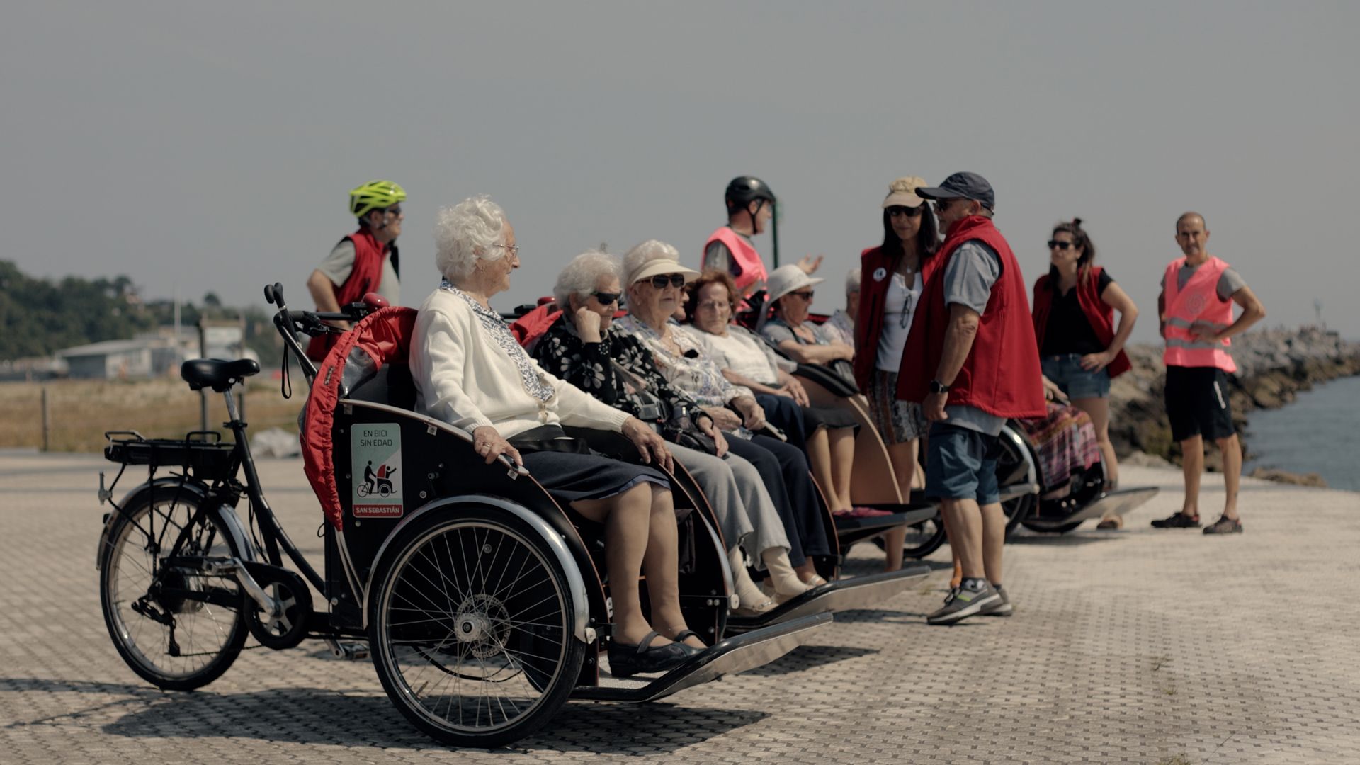 Grupo de personas montadas en los triciclos y los pasajeros al lado, cerca del mar